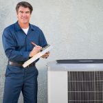 Technician assessing air conditioning unit on exterior wall for Hancock & Son HVAC services.