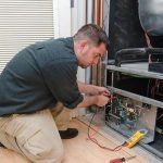 Technician using a multimeter on HVAC wiring indoors at Hancock & Son Plumbing, Heating and Air Conditioning.
