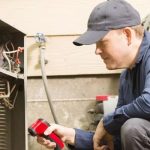 Male technician inspecting HVAC system with tools at Hancock & Son Plumbing, Heating and Air Conditioning in Salisbury, MD.