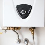 Water heater unit with black control knob and copper piping by Hancock & Son Plumbing, Heating and Air Conditioning.