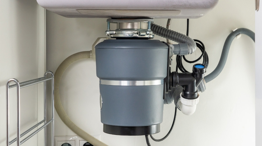 Garbage disposal unit installed under kitchen sink, showcasing plumbing connections and maintenance considerations for optimal performance.